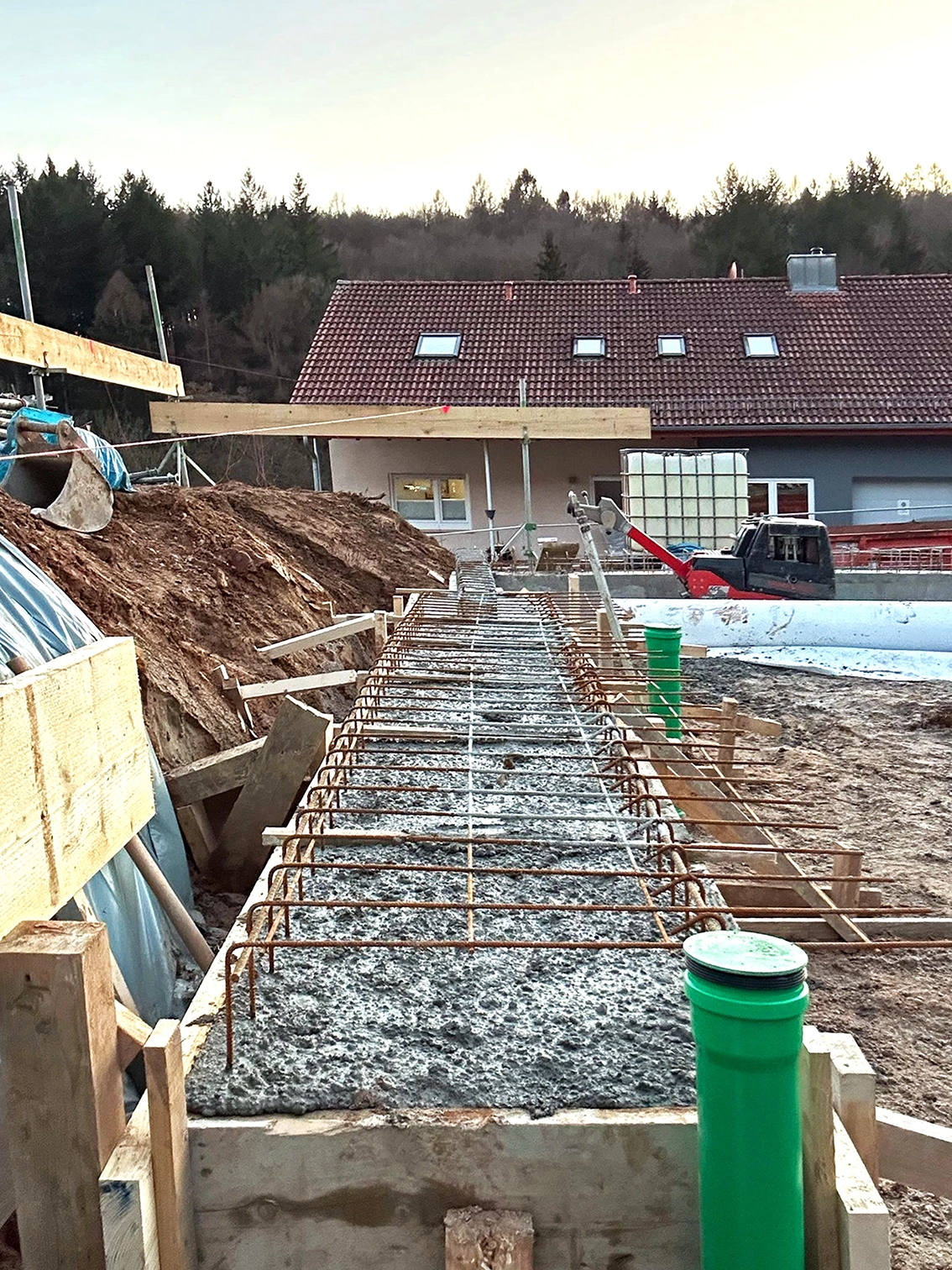 DE_United-Architektur-Start-Construction-House2 Baufortschritt auf der Baustelle mit dem Gießen des Betons für eine Streifenfundamentierung mit Stahlbewehrung auf einem Wohngrundstück.