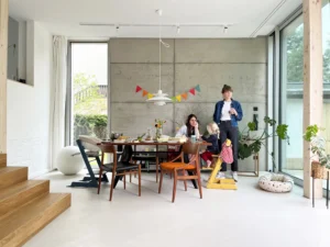 Moderne Esszimmer-Inneneinrichtung mit einer Sichtbetonwand, minimalistischen Designmöbeln, großen bodentiefen Fenstern und hellem, offenem Raumkonzept.