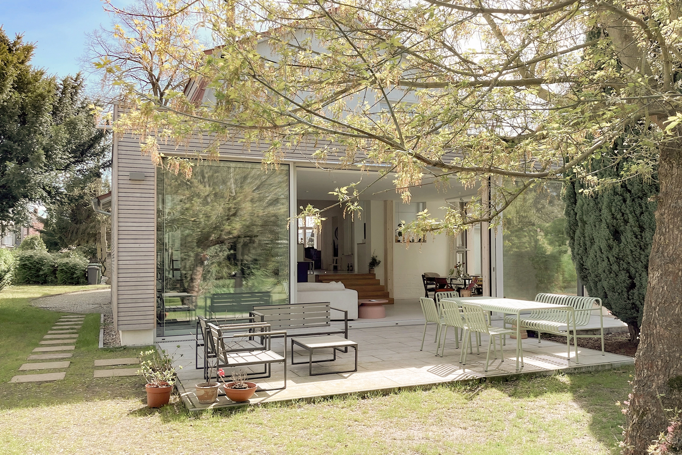 DE_United-Architektur-Yew Tree Living-terrasse1 Minimalistischer moderner Anbau in Berlin mit großen Glasschiebetüren, Holzfassade und integrierter Gartenterrasse.