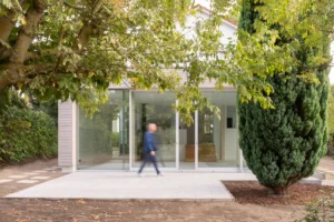 Minimalist modern house extension in Berlin with large sliding glass doors, wooden cladding, and an integrated garden terrace.