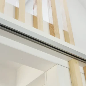Architectural close-up of custom interior carpentry featuring light wood slats, integrated sliding door tracks, and minimalist white finishes.
