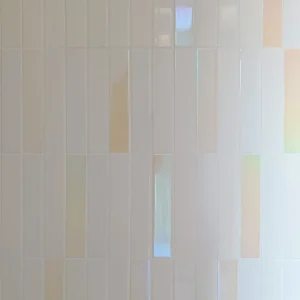 Minimalist bathroom wall featuring vertical iridescent white ceramic tiles with subtle pastel rainbow reflections.