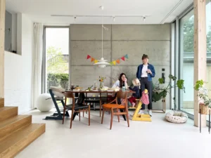 Modern dining room interior featuring an exposed concrete wall, minimalist design furniture, large floor-to-ceiling windows, and bright open space.