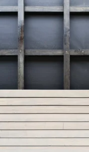 Architectural detail of a sustainable wooden facade under construction, showing horizontal timber cladding slats over a black insulation layer.