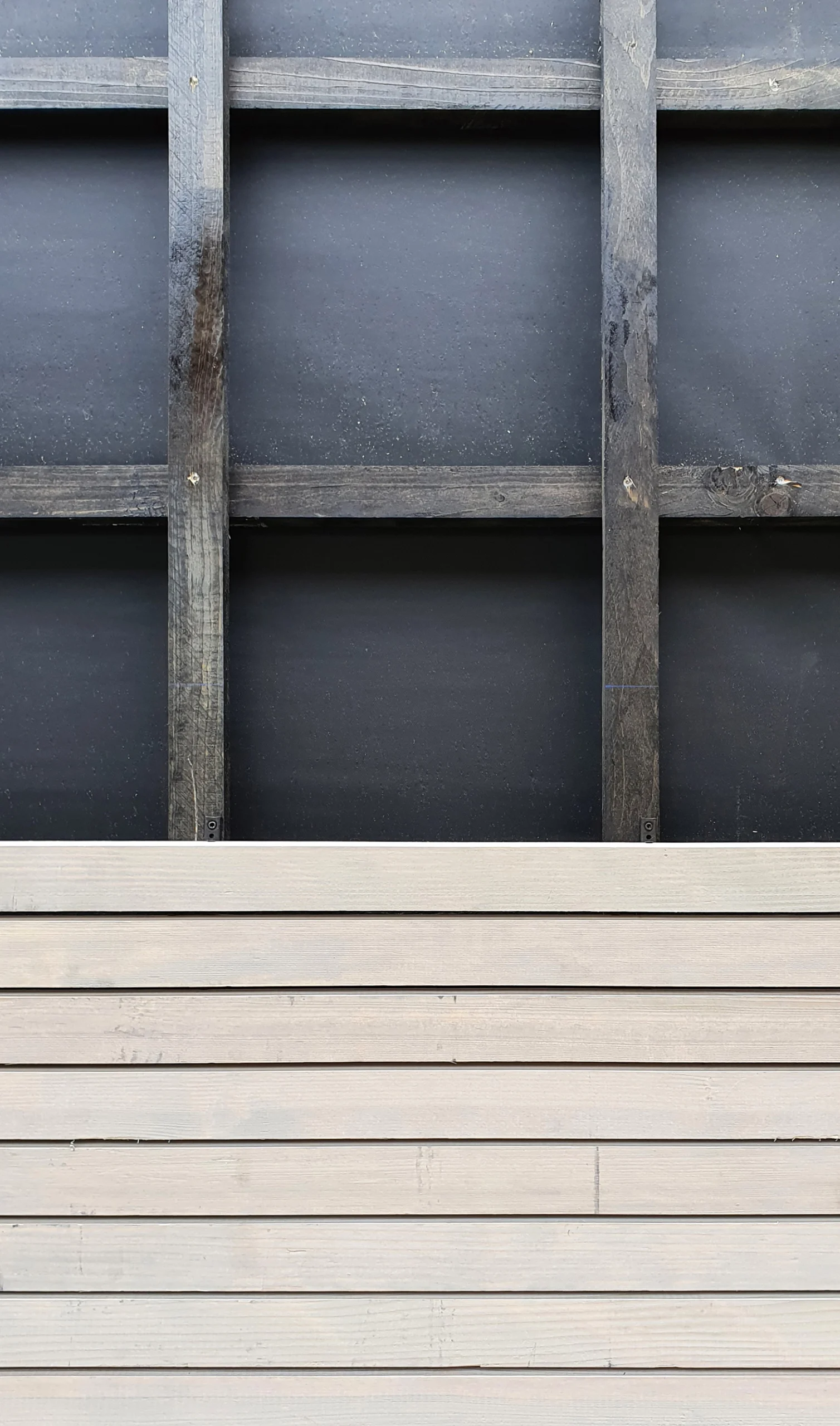 EN_United-Architektur-Yew Tree Living-horizontale Holzverschalung01 Architectural detail of a sustainable wooden facade under construction, showing horizontal timber cladding slats over a black insulation layer.
