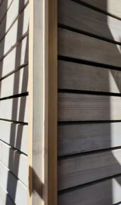 Close-up architectural detail of a corner joint on a modern timber-clad facade, highlighting the precise horizontal wood slats and natural shadow play.